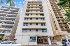 A multi-story building with a ground-level entrance, balconies, and a visible storefront with signage. - Waikīkī Beach Loft Near Restaurants (Honolulu)