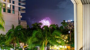 Ein mehrstöckiges Gebäude mit Balkonen, umgeben von Palmen und einem Nachthimmel mit Feuerwerk.