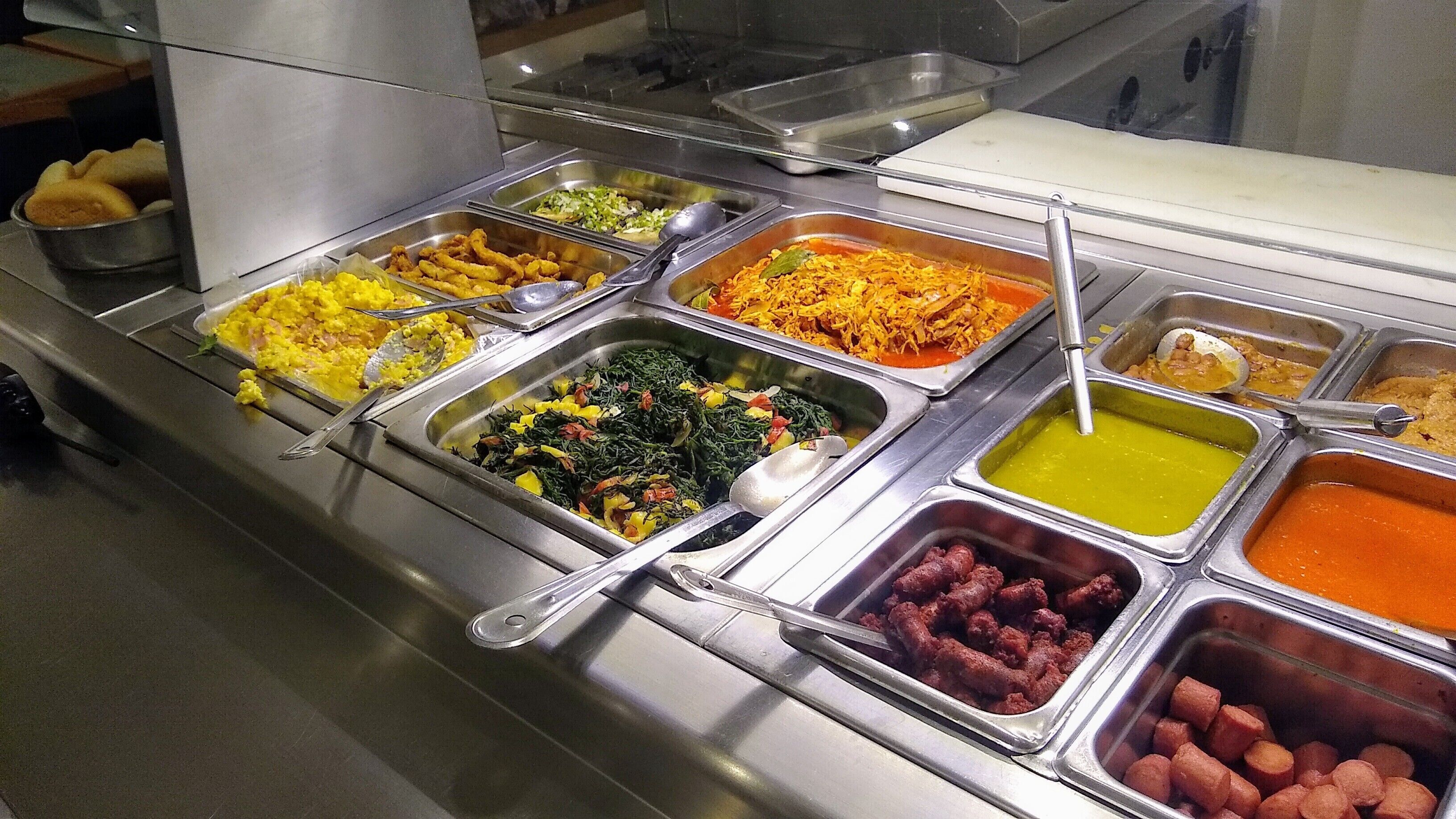 A buffet with various food options including salads, meats, and rice dishes.