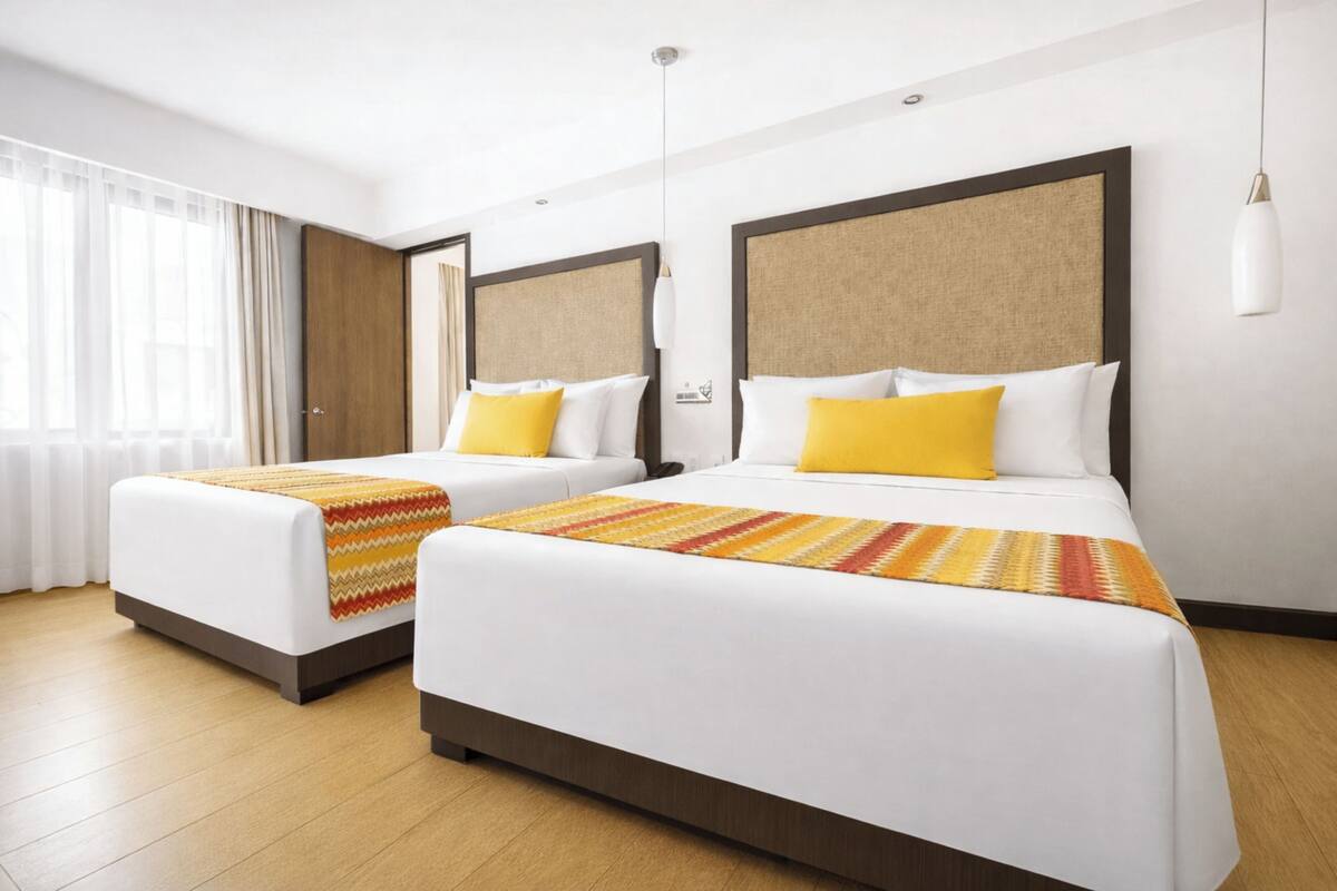 A hotel room with two beds, a large window with curtains, and a wooden floor.