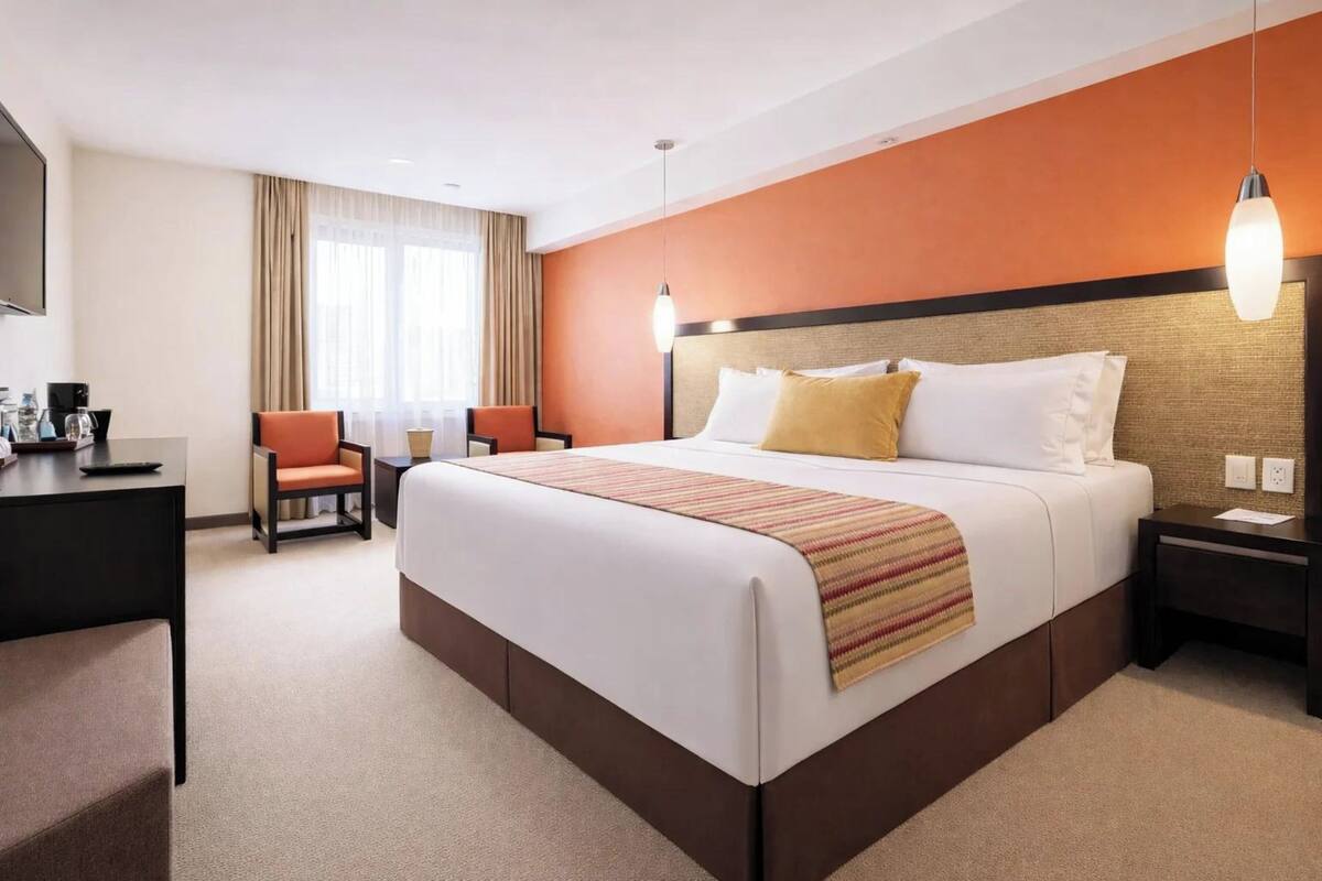 A hotel room with a large bed, a desk, a chair, and a television.
