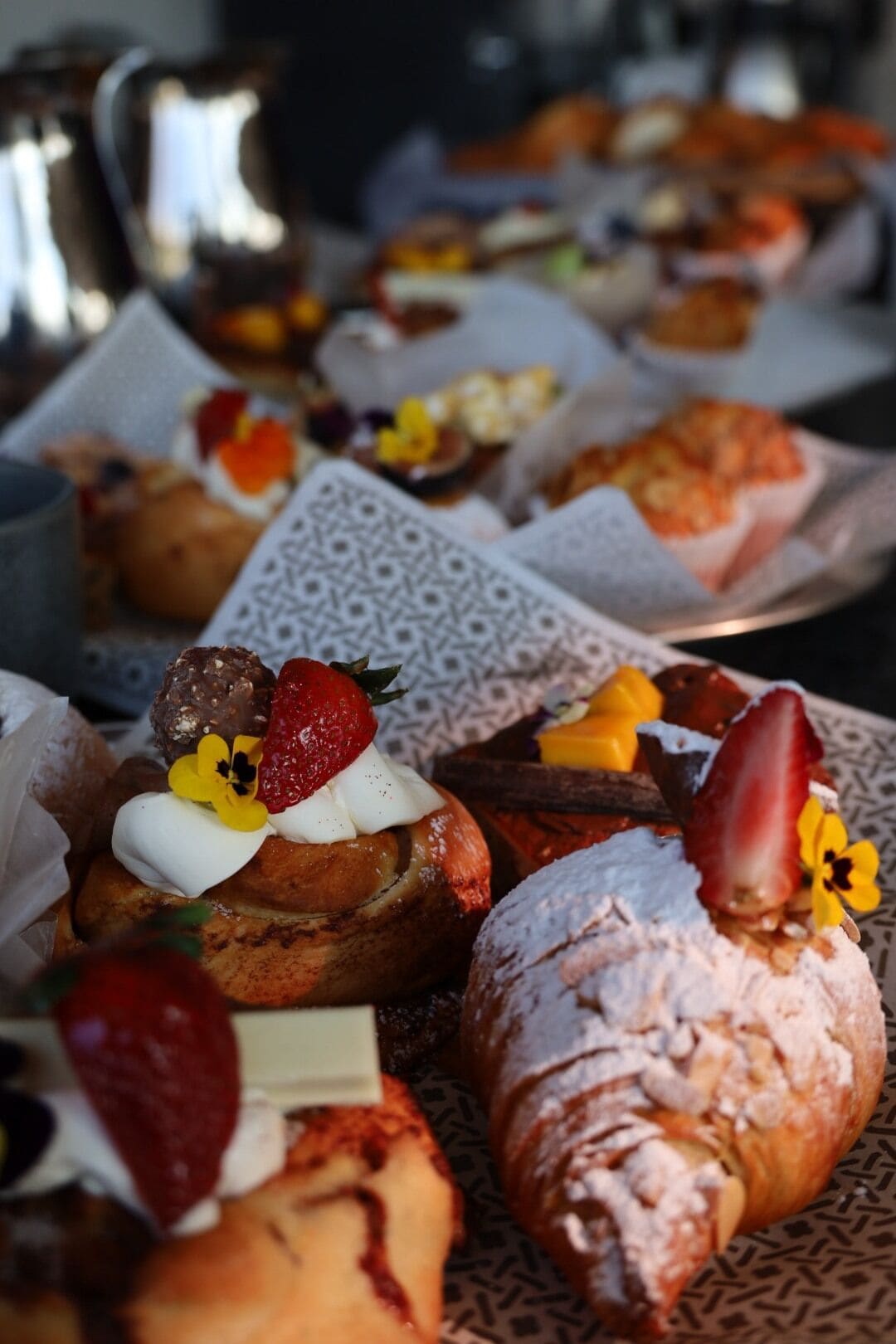 A variety of pastries and desserts on a tray, including a croissant with powdered sugar and a strawberry.