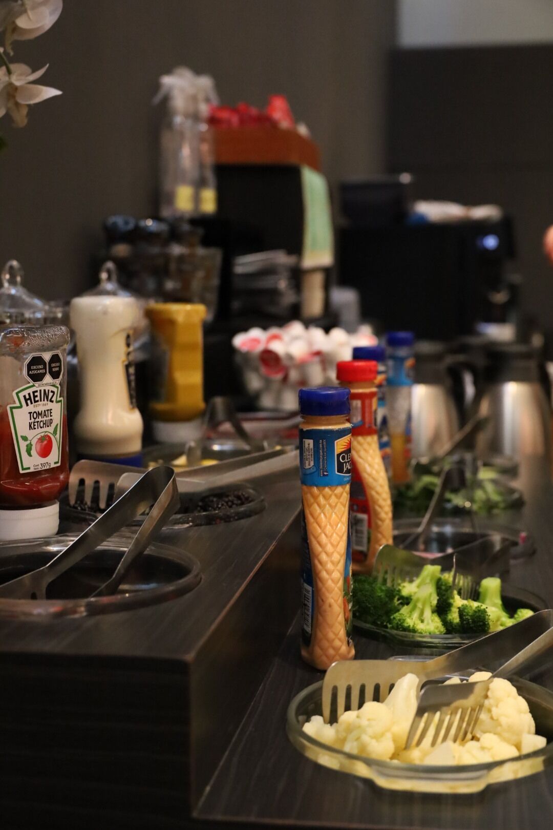 Una mesa de buffet con salsas, una ensalada y un utensilio para servir.