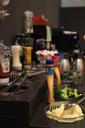 A buffet setup with condiments, a salad, and a serving utensil.