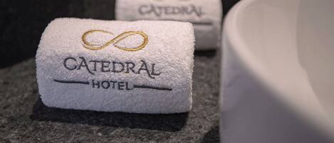 A folded towel with 'CATEDRAL HOTEL' embroidered on it, placed on a dark countertop.