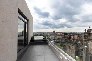 Un balcon avec vue sur la ville, de grandes fenêtres et des plantes en pot.