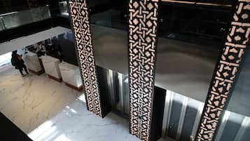 Een moderne lobby met een marmeren vloer, een receptiebalie en een decoratief paneel met een patroon.