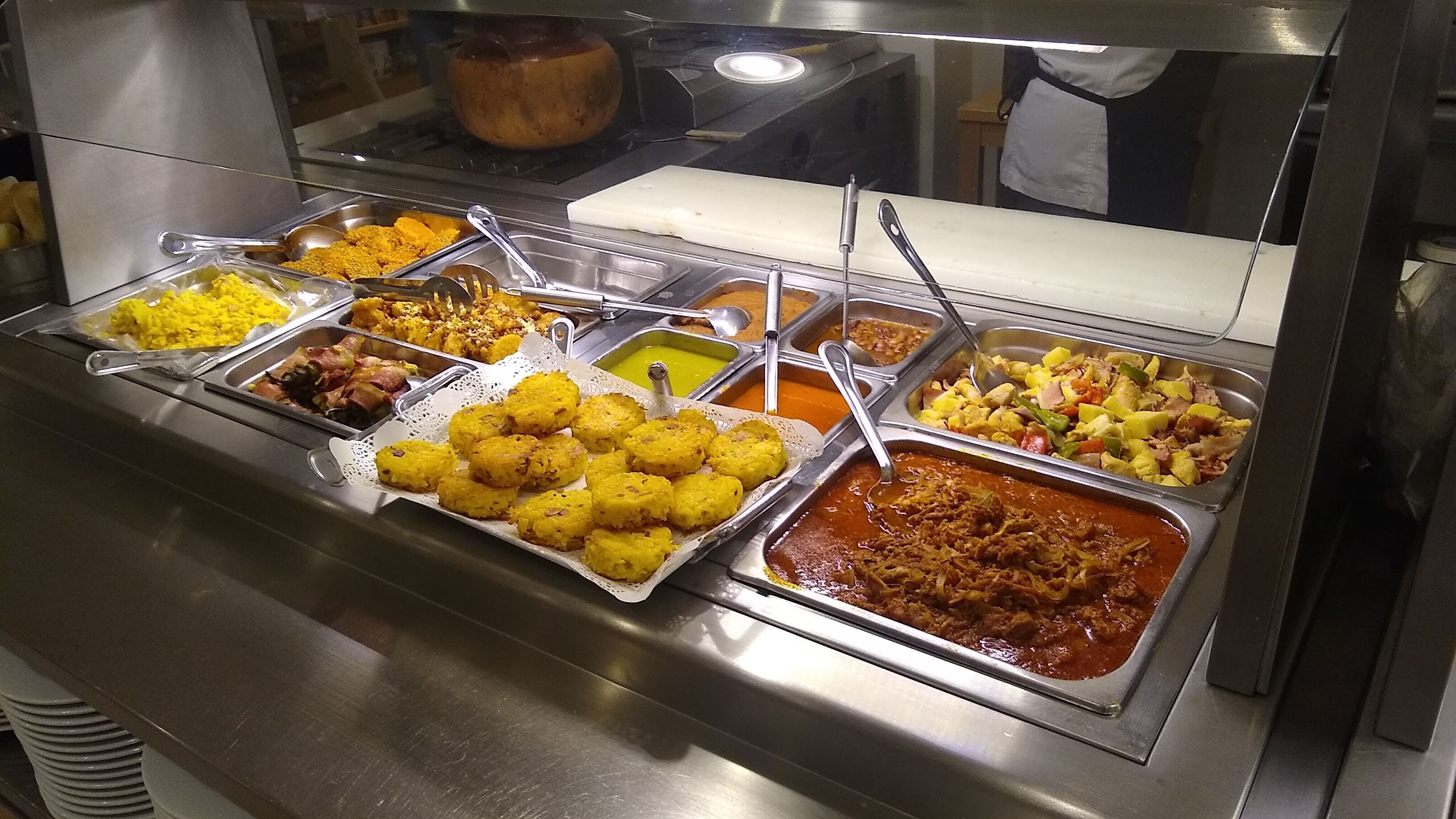 A buffet with various dishes including yellow rice, a red curry, and other mixed dishes.