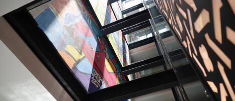 A modern interior with a glass ceiling, geometric wall patterns, and a staircase.