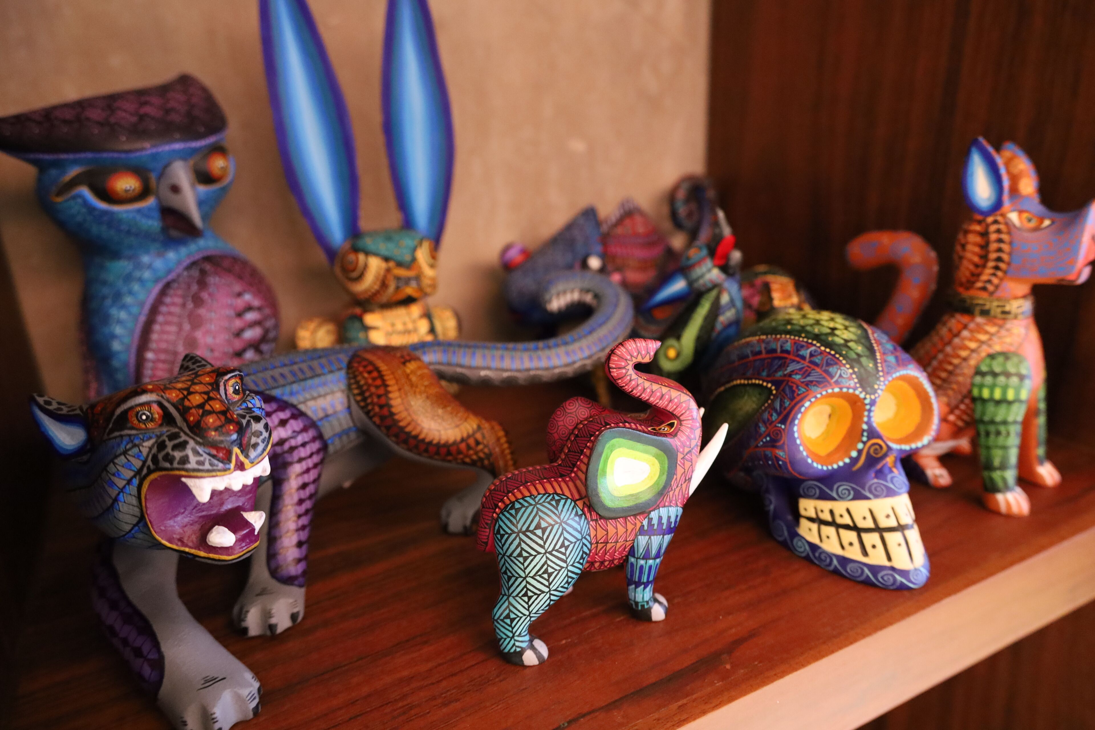 Une collection de figurines aux couleurs vives et aux motifs complexes, disposées sur une étagère en bois.