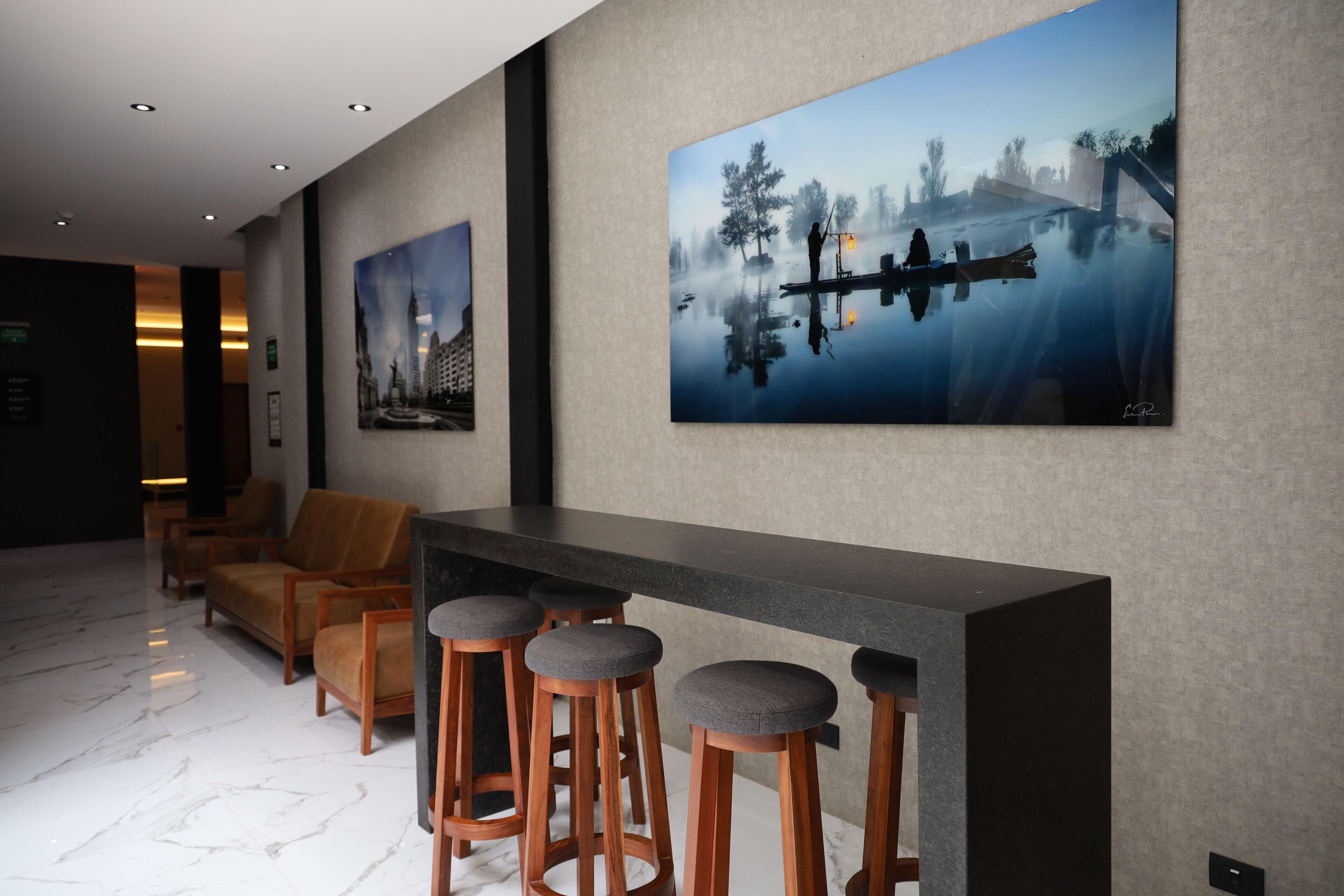 Un hall d’entrée moderne avec un comptoir d’accueil, des tabourets de bar et un espace salon.