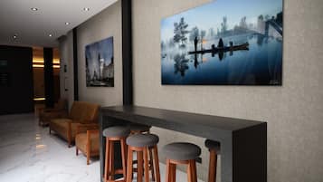 Un hall d’entrée moderne avec un comptoir d’accueil, des tabourets de bar et un espace salon.