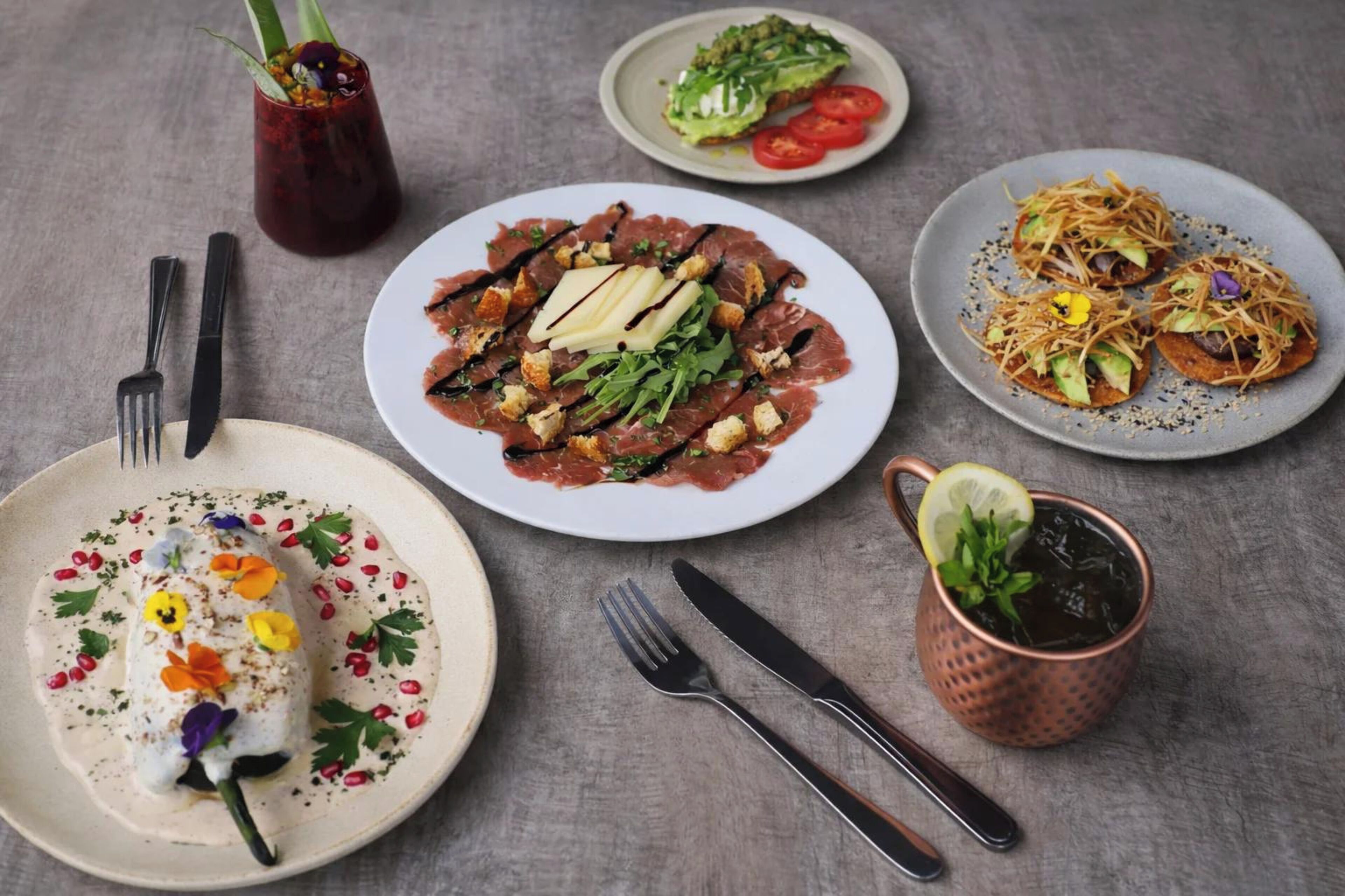 A table with various dishes, utensils, and a drink.