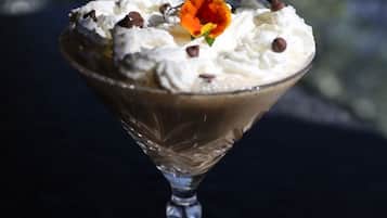 Postre en vaso con crema batida y trozos de chocolate, decorado con una flor.
