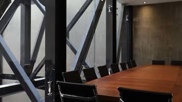 Une salle de conférence dotée d’une grande table en bois, de chaises noires et offrant une vue sur l’extérieur grâce à de larges fenêtres.