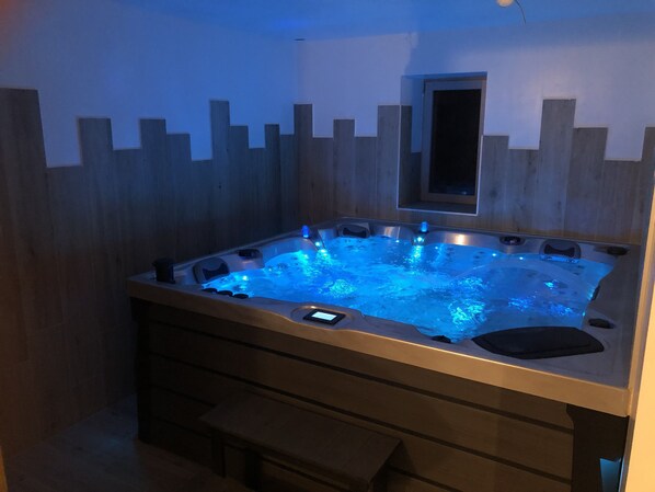Ein Whirlpool mit einer Holzwand und einem kleinen Fenster darüber.
