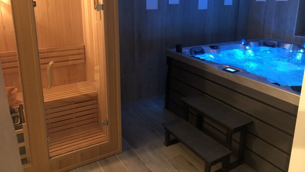 Un sauna en bois avec des bancs et un jacuzzi doté d’un éclairage bleu.