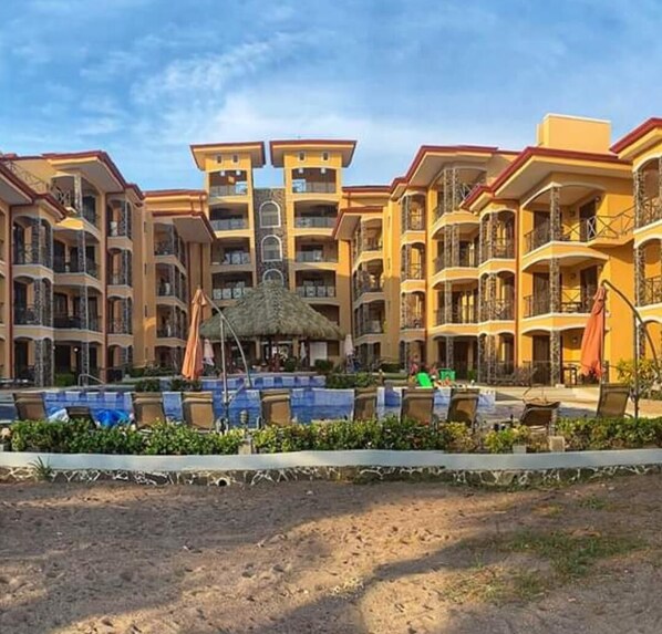 A multi-story hotel with balconies, a swimming pool, and outdoor seating areas. - Beachfront Jaco Condos - Fully Equipped - 6 Pax (Jacó)