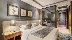 Una habitación de hotel moderna con una cama grande, lámparas de noche, una mesita de noche de madera y cuadros en la pared.