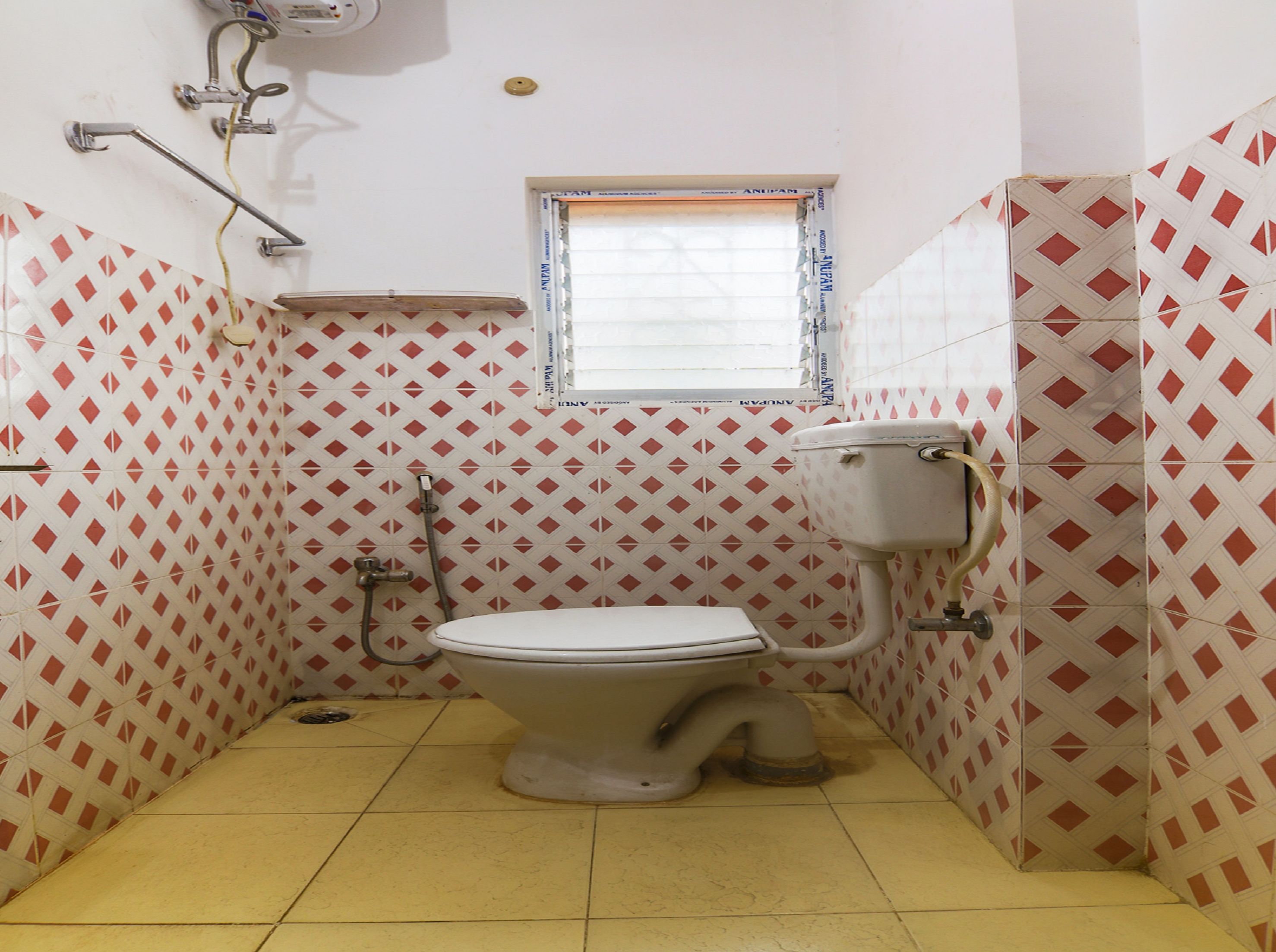A small bathroom with a toilet, a window, and patterned walls.