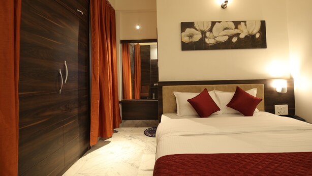 A hotel room with a bed, a wardrobe, a painting, and a nightstand. - Magnolia Inn near GNRC & Secretariat, GS Rd (Guwahati)
