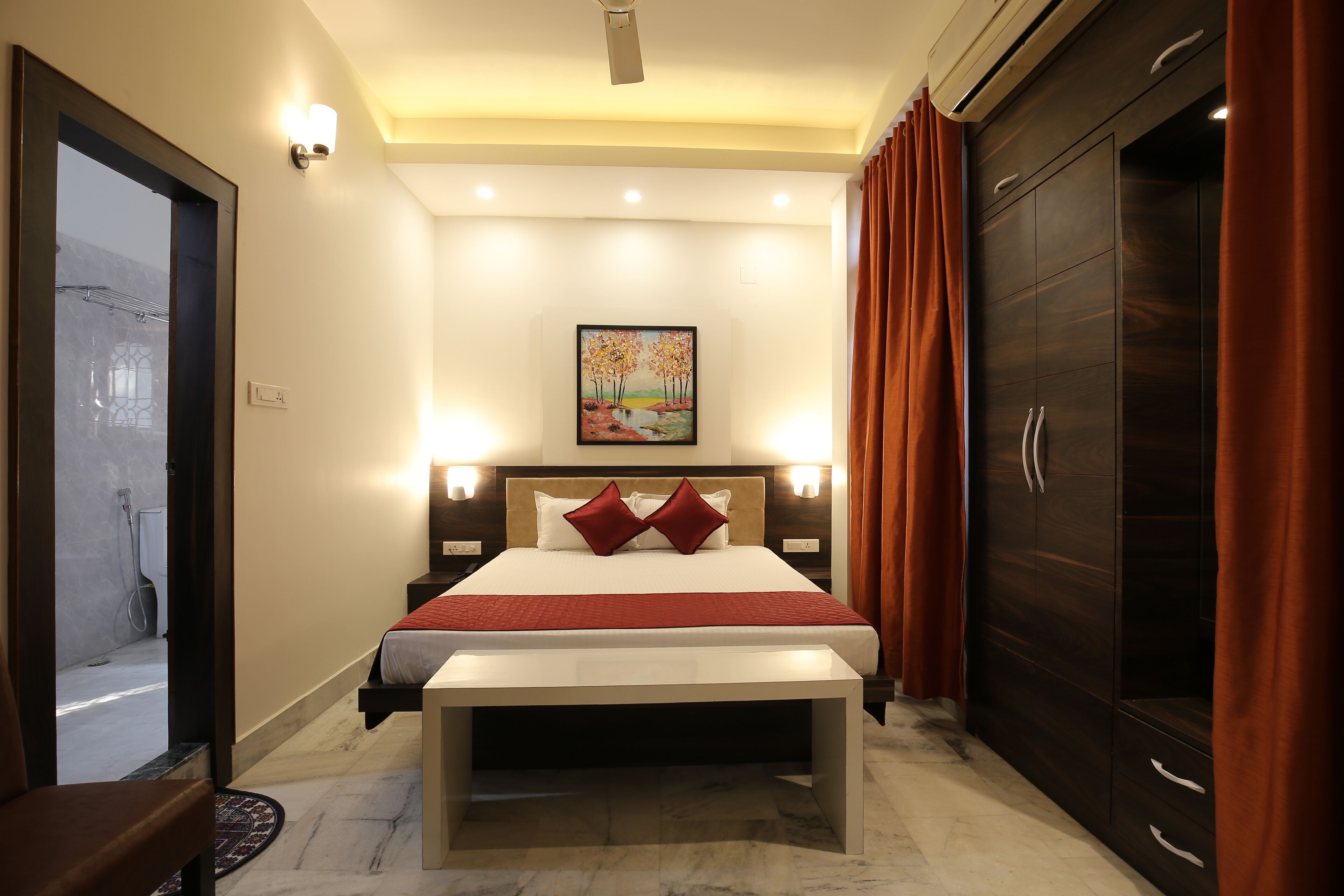 A hotel room with a bed, bedside lamps, a painting on the wall, and a wardrobe.