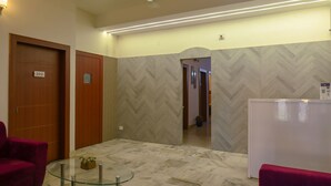 A hotel lobby with a marble floor, a glass coffee table, a ceiling fan, and wooden doors. - Magnolia Inn near GNRC & Secretariat, GS Rd (Guwahati)