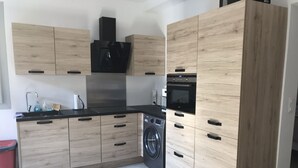 Una cocina moderna con armarios de madera, lavadora, microondas y fregadero.