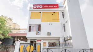 Un edificio de varios pisos con un llamativo letrero rojo y blanco del Hotel OYO Golden Star.