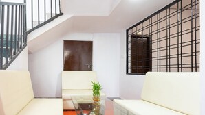 Una sala de estar moderna con una mesa de centro de vidrio, sofás blancos, una escalera y vistas al exterior.