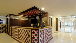 A reception area with a counter, a television, and a patterned wall. - OYO 43619 Sahasra Residency (Hyderabad)
