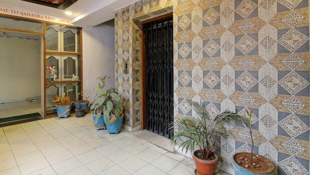 A hotel entrance with a patterned wall, potted plants, and a sign reading "Sahasra Residency". - OYO 43619 Sahasra Residency (Hyderabad)