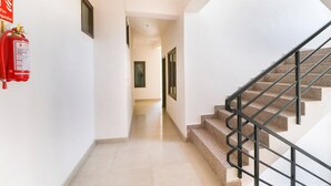 A hallway with a fire extinguisher, a staircase with metal railings, and a door at the end. - OYO 43300 Spring Woods Suites (Mohali)