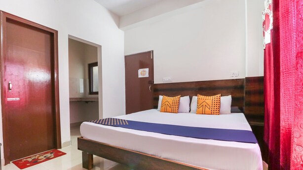 A hotel room with a bed, a wooden headboard, and a red curtain. - OYO 43300 Spring Woods Suites (Mohali)