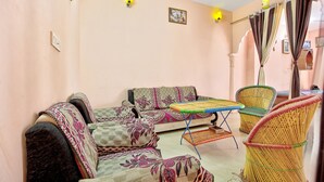 Un salón con un sofá, una mesita y una silla de mimbre.