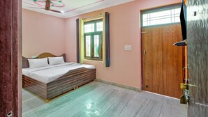 Un dormitorio con cama, ventilador de techo, ventana con cortinas y puerta de madera.