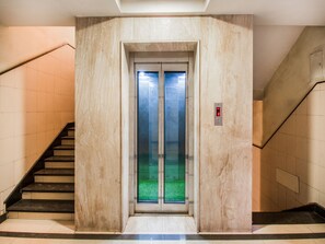 An elevator in a building with a marble wall and a glass door. - OYO VSK145 Ssg Residency (Visakhapatnam)