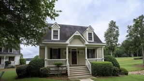 A two-story house with a front porch, a small front yard, and a pathway leading to the door.