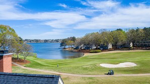 A golf course with a lake, a sand bunker, and a clubhouse.