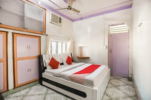 Une chambre à coucher comprenant un lit, une armoire, un ventilateur de plafond, une fenêtre et une porte.