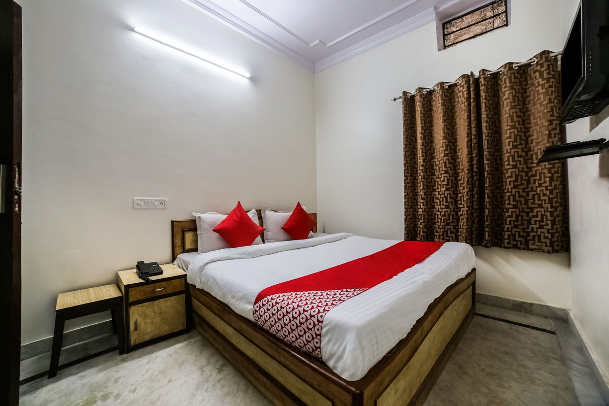 A neatly arranged bedroom with a wooden bed, a bedside table, and a TV mounted on the wall.