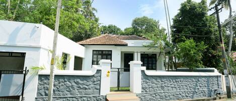 A two-story house with a stone wall and a tiled roof.