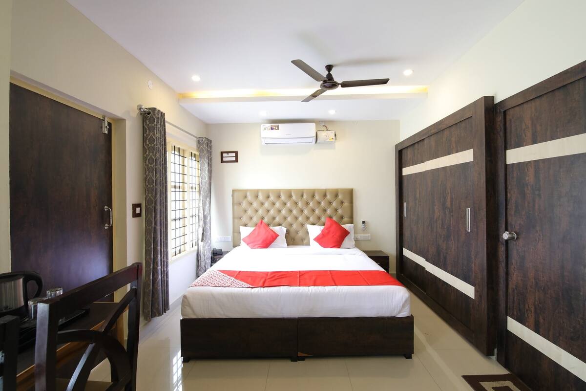 A bedroom with a bed, a ceiling fan, an air conditioning unit, and a wardrobe.
