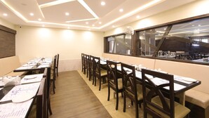 A conference room with long tables, chairs, and a large window. - OYO 28093 Royal Sand (Mysore)