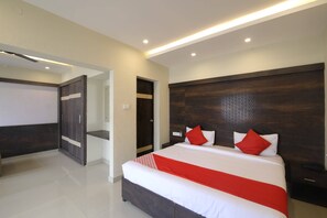 A modern bedroom with a large bed, a wardrobe, and a door leading to a bathroom. - OYO 28093 Royal Sand (Mysore)