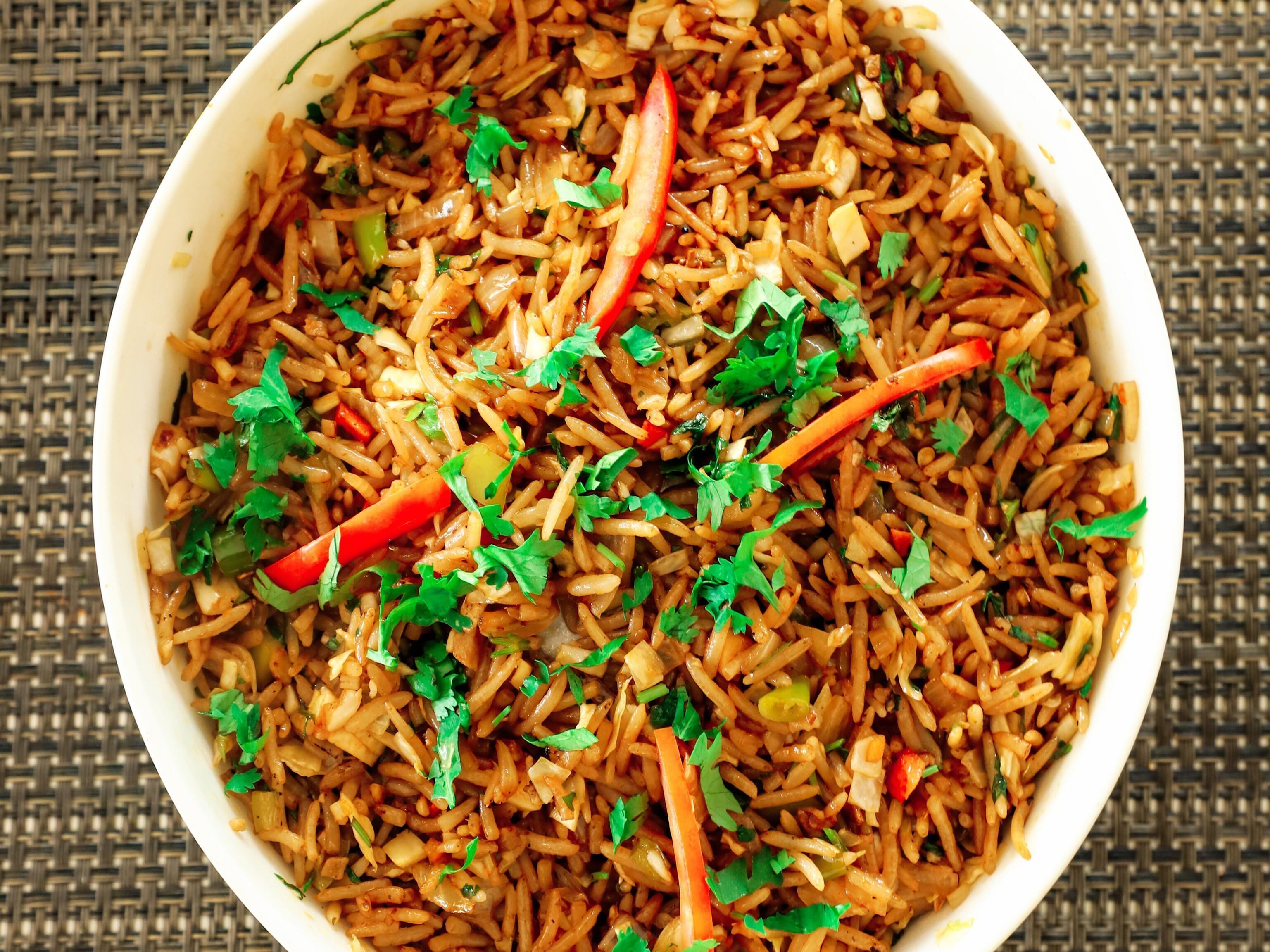 Un tazón de arroz frito con verduras y hierbas.