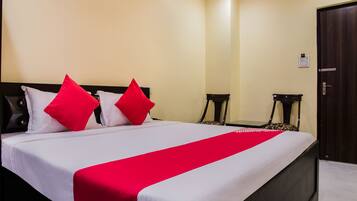 A hotel room with a large bed, two bedside tables, a wooden wardrobe, and a door.