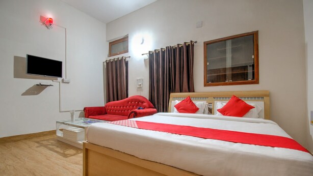 A hotel room with a bed, a red armchair, a television, and curtains. - OYO Flagship 23420 Patliputra Heritage Guest House (Patna)