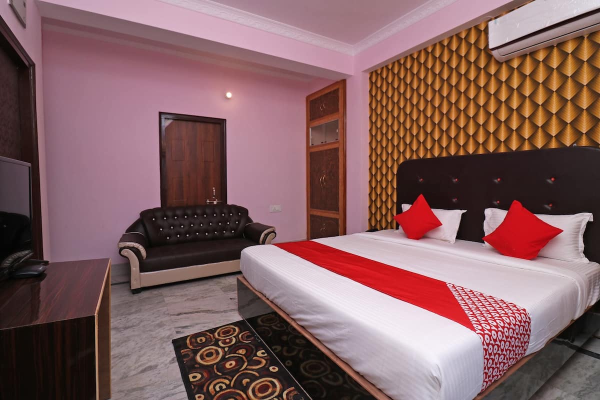 Une chambre d’hôtel avec un lit, un canapé, un bureau et un tapis à motifs.