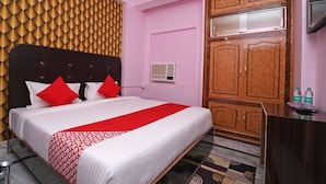 Een hotelkamer met een bed, een houten kledingkast, een bureau en een wandairconditioner.